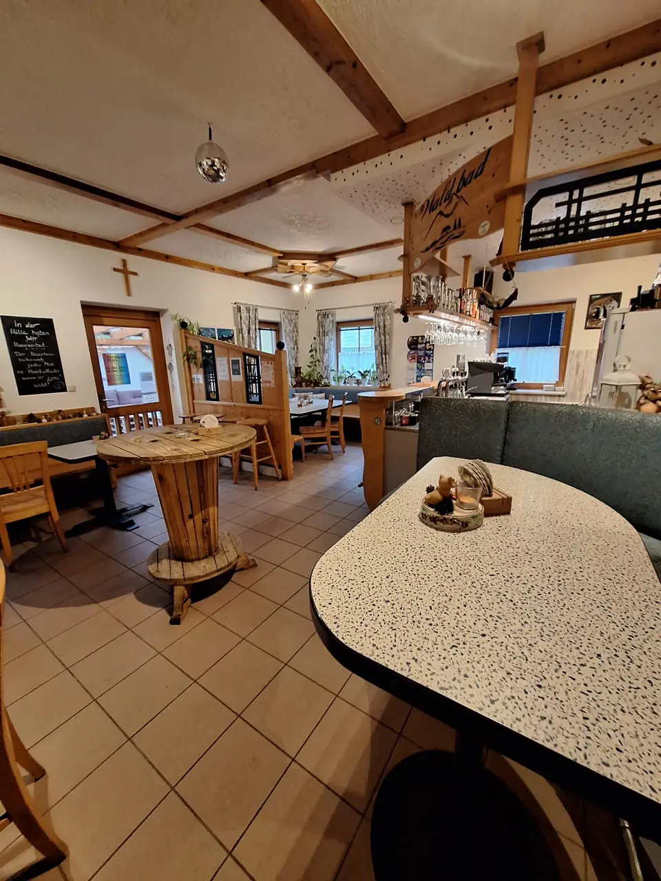 Gaststube des Waldbad-Buffets mit Sitzbänken, Holztischen und Theke
