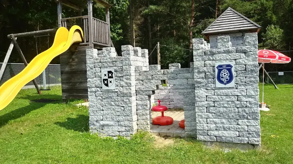 Spielplatz mit Granitburg, gelber Rutsche und Schaukel
